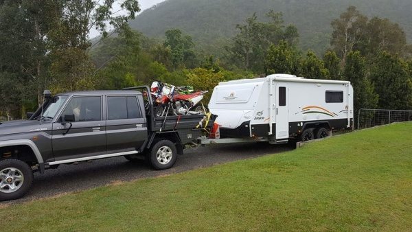 Off-road caravan outfitted with essential gear like winches, recovery tracks, and spare tires, parked outdoors
