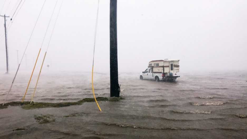 Caravan precariously parked amidst rising floodwaters, capturing the power and danger of natural disasters