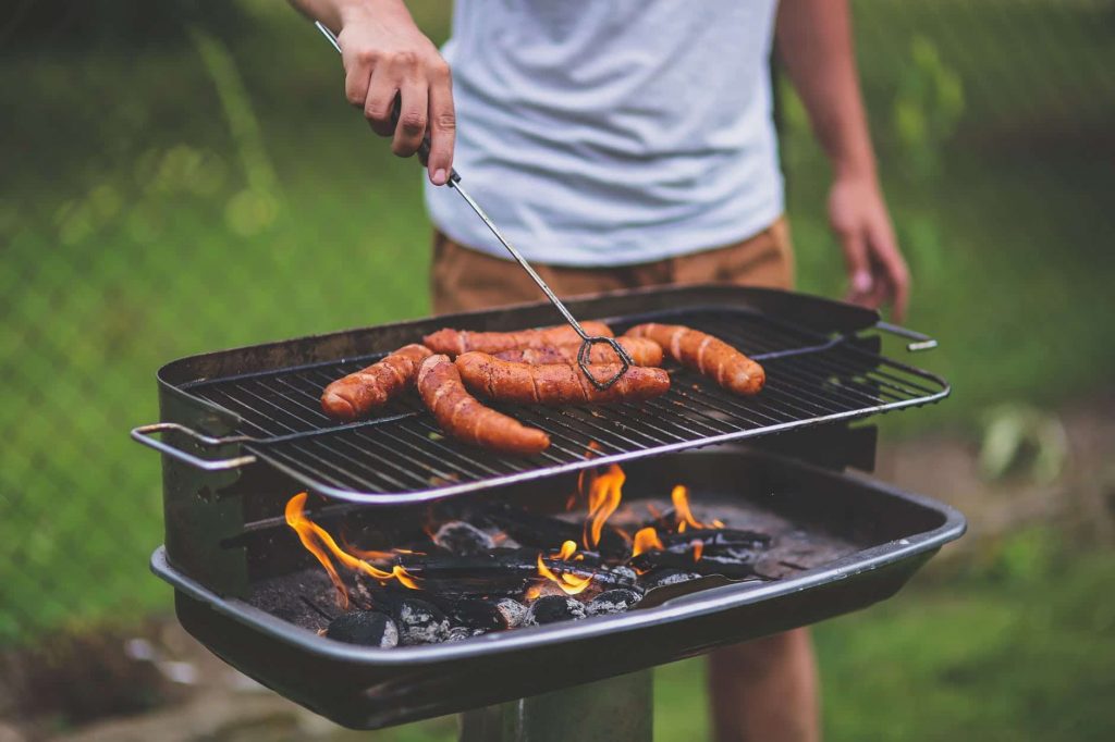Juicy sausages sizzling on a grill outdoors, perfect for a summer barbecue