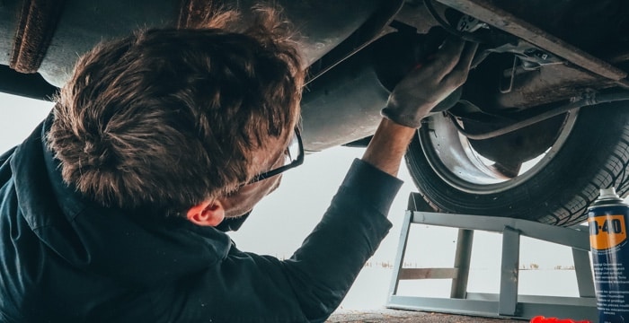 Technician checks tire tread wear and inflation on a lifted car