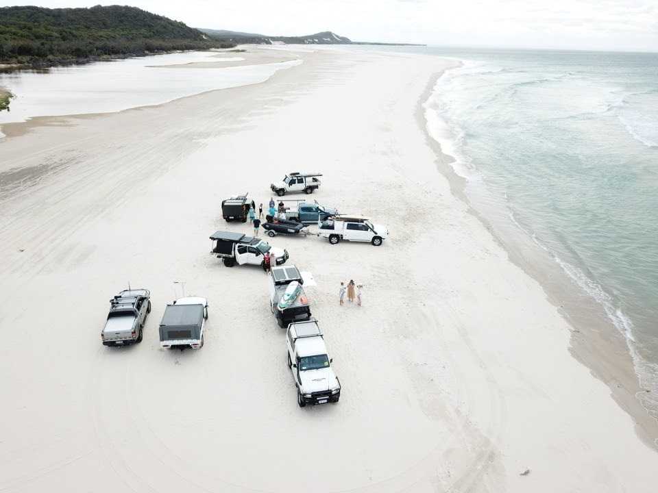 White RV parked on a scenic overlook near a beach with mountains in the background