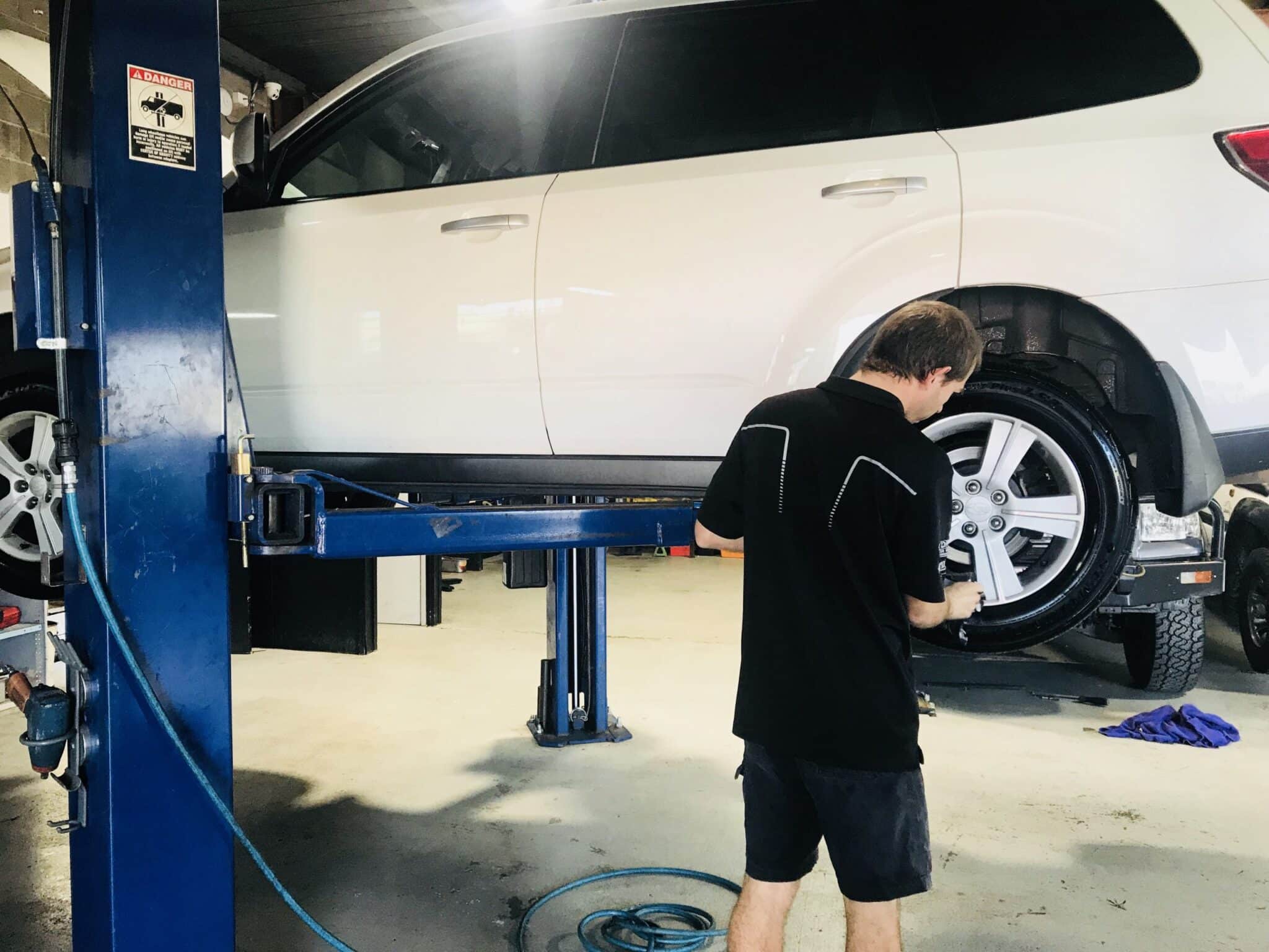 Technician examines car wheels on a lift, ensuring their condition and alignment