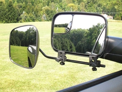 Rearview mirror reflection shows securely attached caravan hitch, promising a stress-free adventure