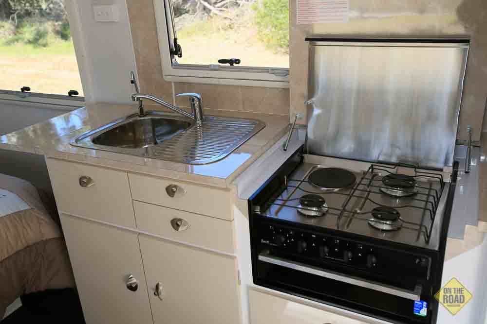 Compact caravan kitchen with a stainless steel sink and two-burner stovetop