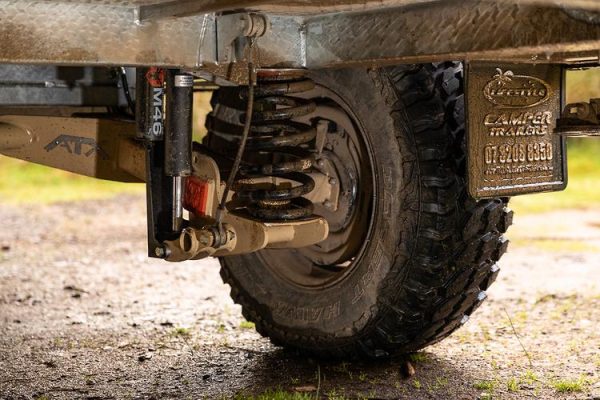 Close-up view of gleaming rims and mud-splattered caravan tires on a dusty dirt road