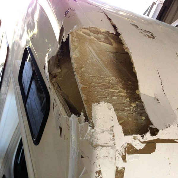 Damaged fiberglass caravan undergoing repair in workshop