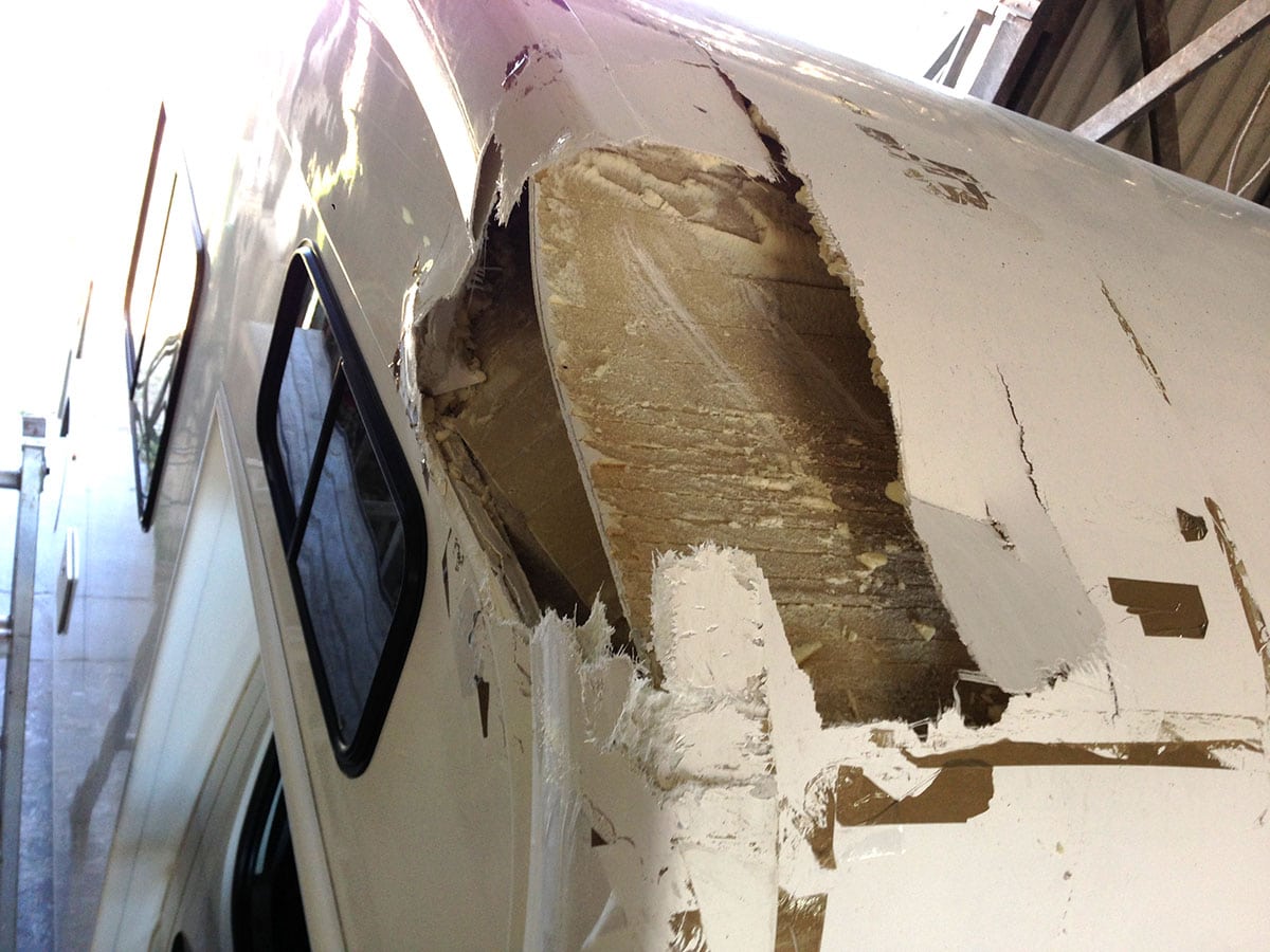 Damaged fiberglass caravan undergoing repair in workshop