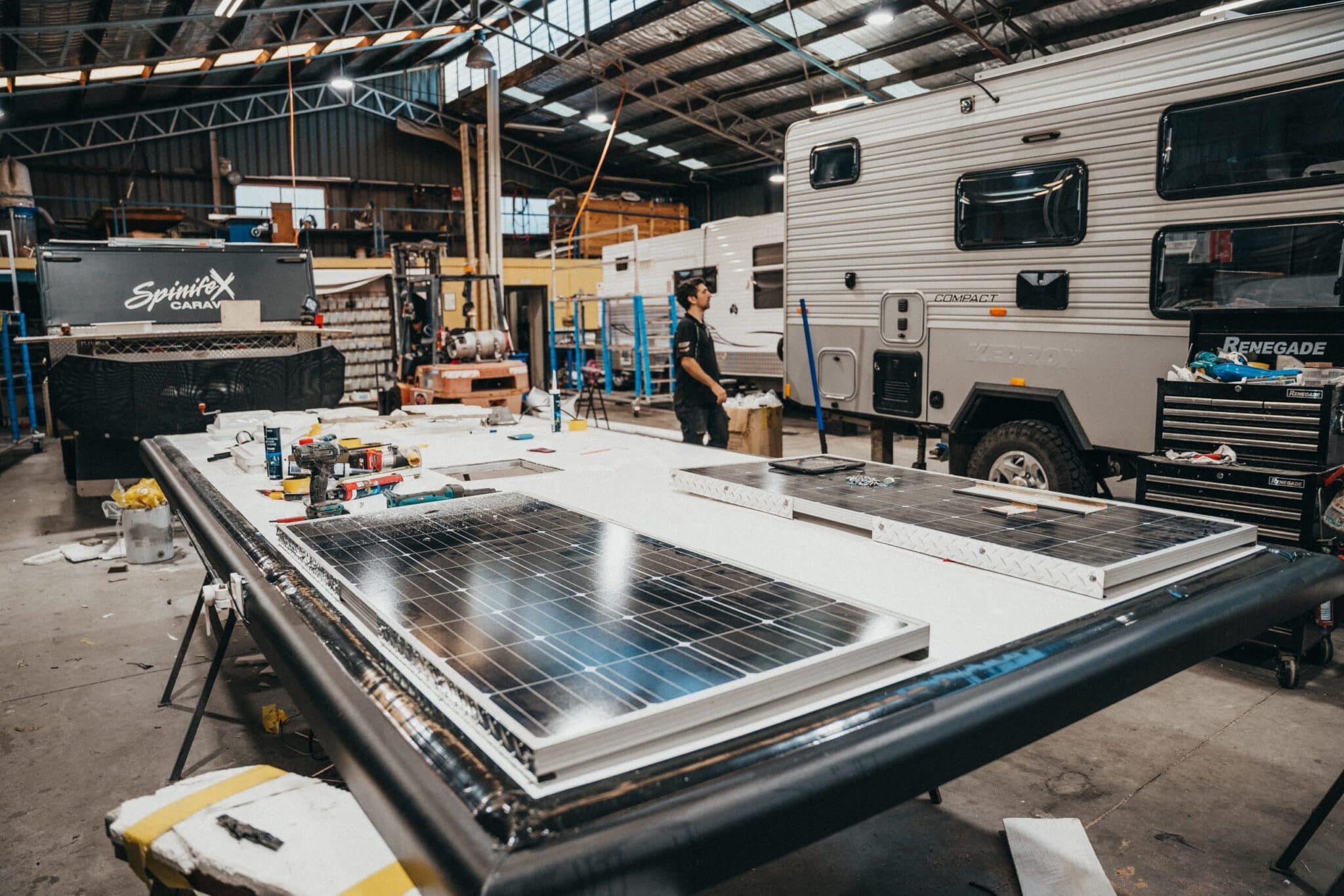 Keeping your caravan energy efficient: Two technicians service and reattach a solar panel for continued power