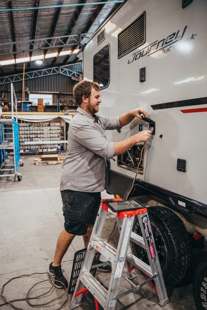 Mechanic diagnosing a caravan issue in a repair shop