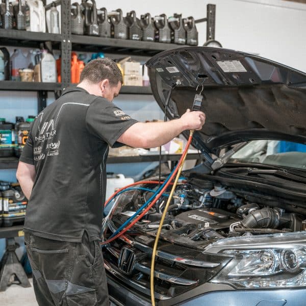 Technician performing engine diagnostics with specialized tools (under the hood)