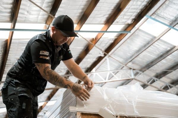 Caravan technician inspects the top of a white vehicle in a workshop