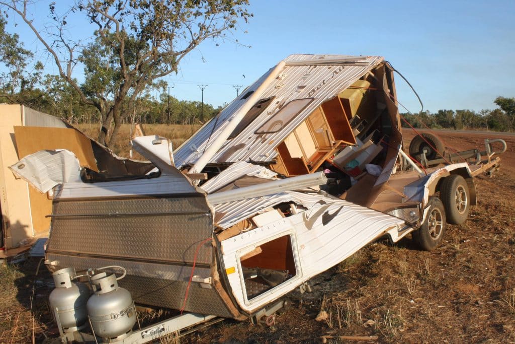 close-up of a wrecked caravan, showcasing its collapsed roof and smashed windows