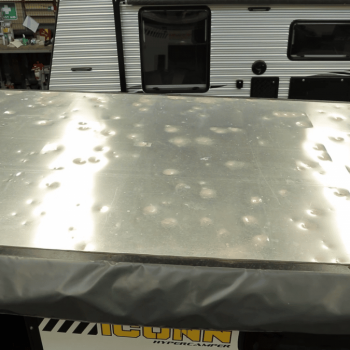 Caravan with its roof exposed, showcasing the extent of hail damage and ongoing repair work.