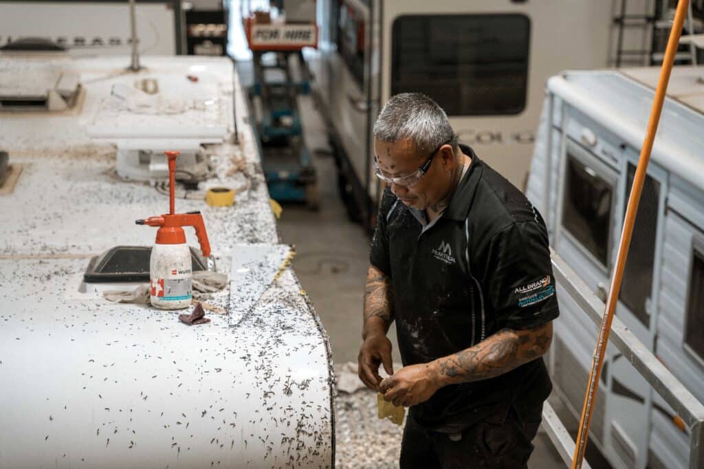 Caravan technician thoroughly cleaning the roof lining inside a workshop, ensuring hygiene and freshness