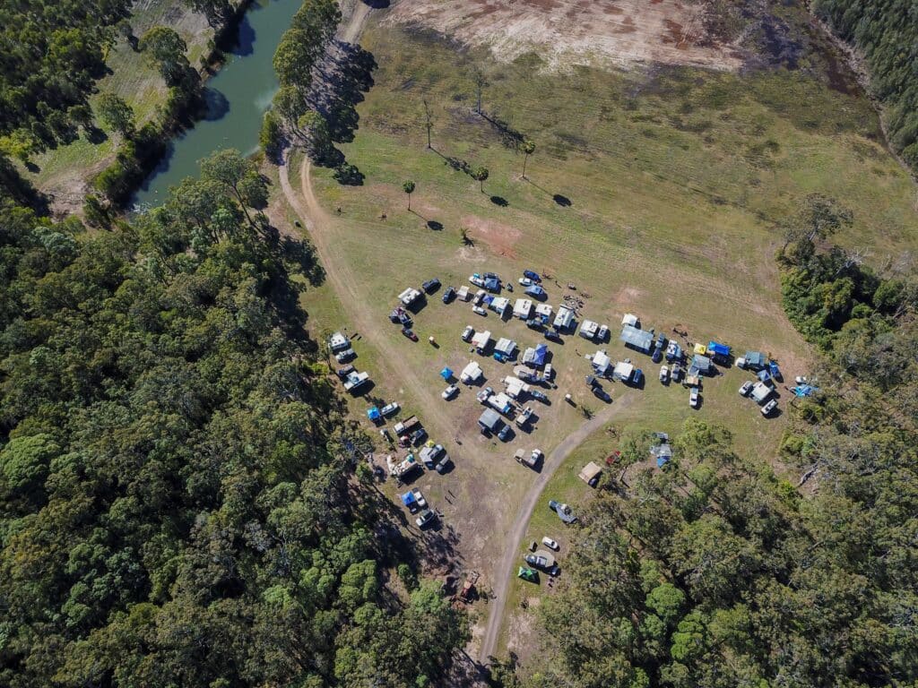 Blue camper trailer parked on a dirt road in a scenic forest clearing