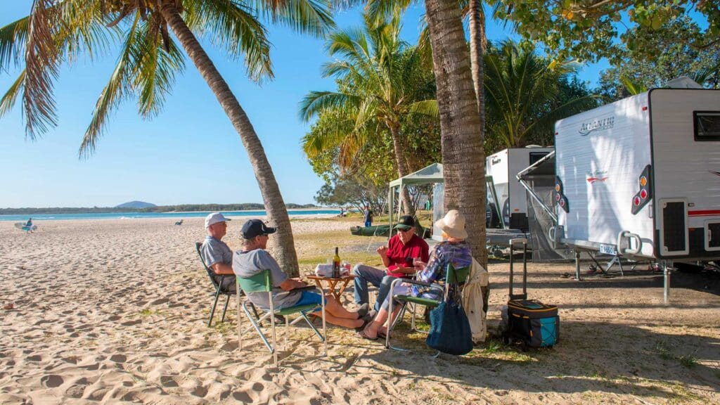 A relaxing moment for a family camping by the ocean, with their caravan parked nearby