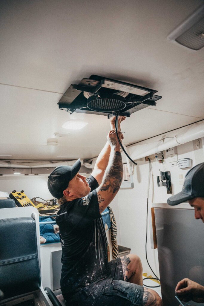 Caravan air conditioning repair in progress: Technician focuses on the ceiling unit for troubleshooting