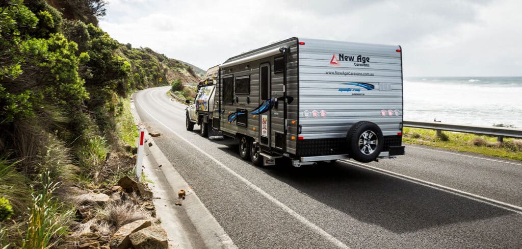 Caravan on a scenic journey, towed along a cemented road with the beach on one side