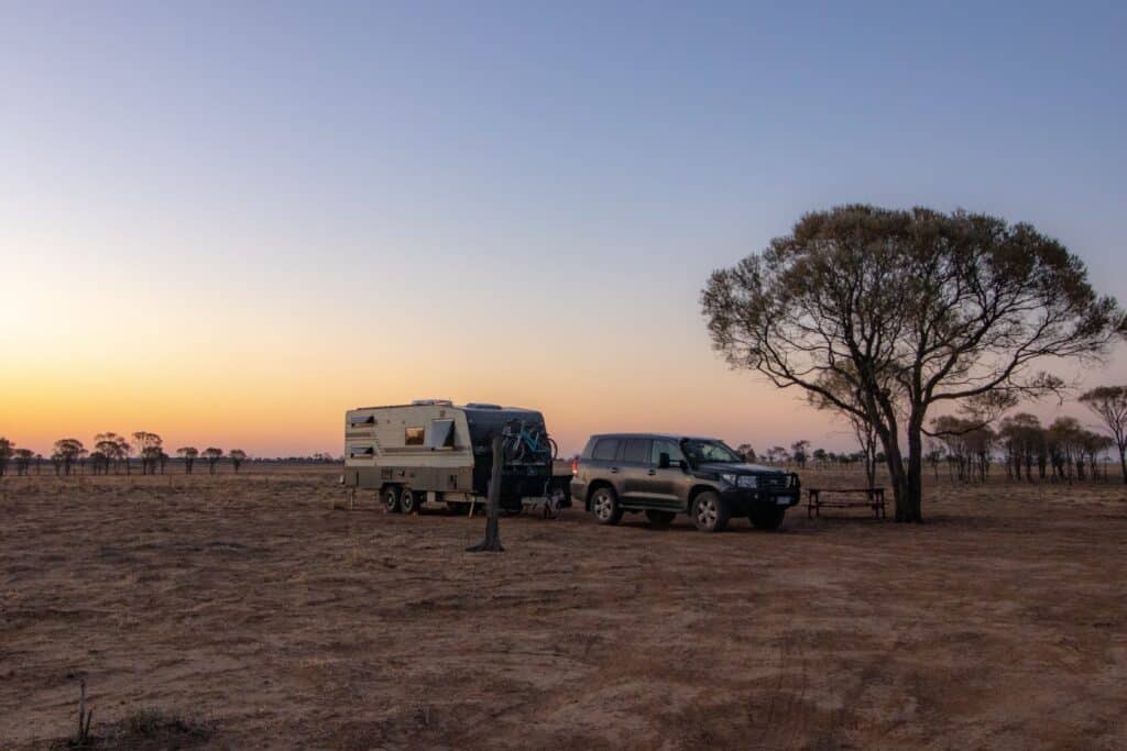 car and trailer, parked in a field at sunset, create a picturesque scene