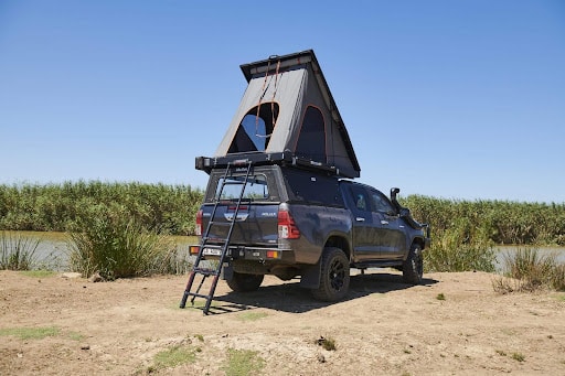 Pickup truck with a rooftop tent parked next to a lake or river