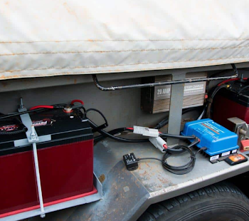 Two black 2V batteries secured beneath a caravan, providing additional power storage for off-grid use.