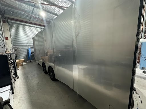 A silver trailer with a brand new aluminum wall parked in a workshop