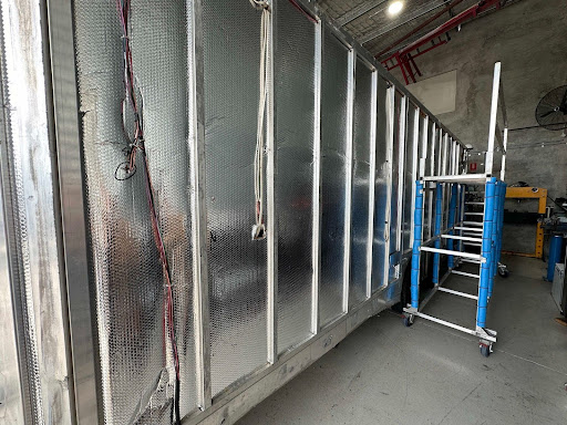 A silver trailer undergoing repairs in a workshop,