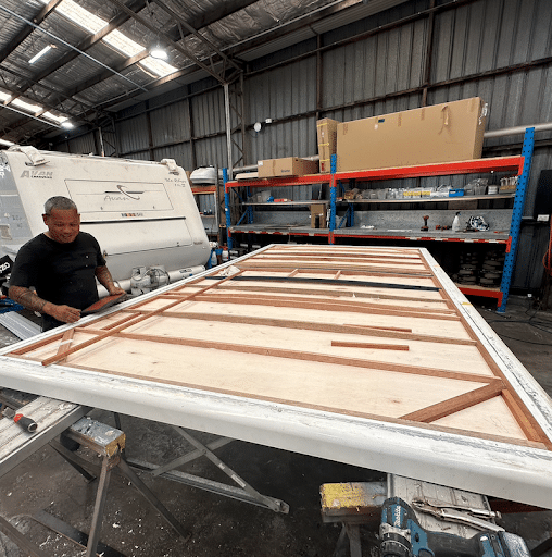 Man concentrates on fixing a ripped canvas on a caravan pop-top roof