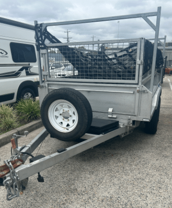 A silver trailer parked on a sunny gravel driveway