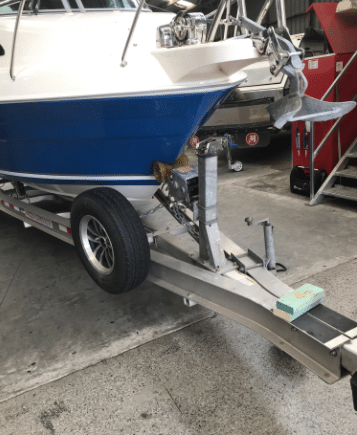 A silver boat trailer parked outside a shop for maintenance