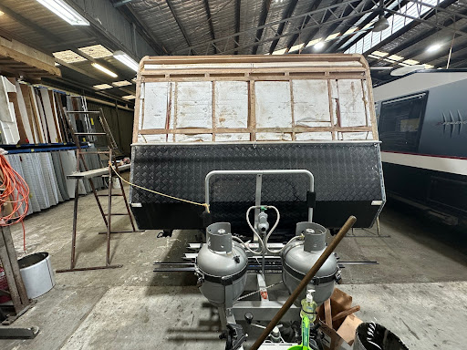 Damaged caravan undergoing repairs in a workshop